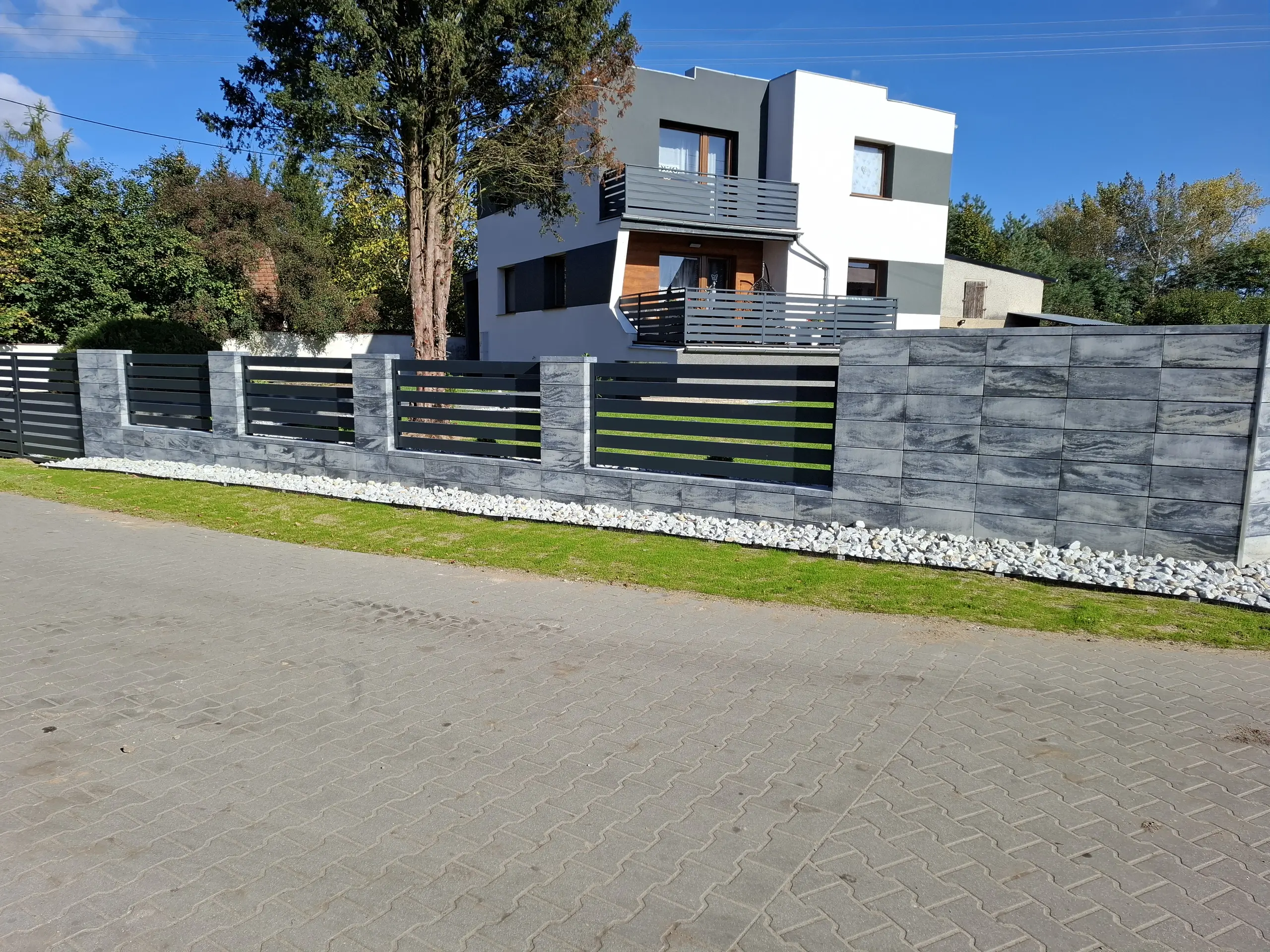 Nowoczesne ogrodzenie żaluzjowe z betonowymi słupkami przed domem
