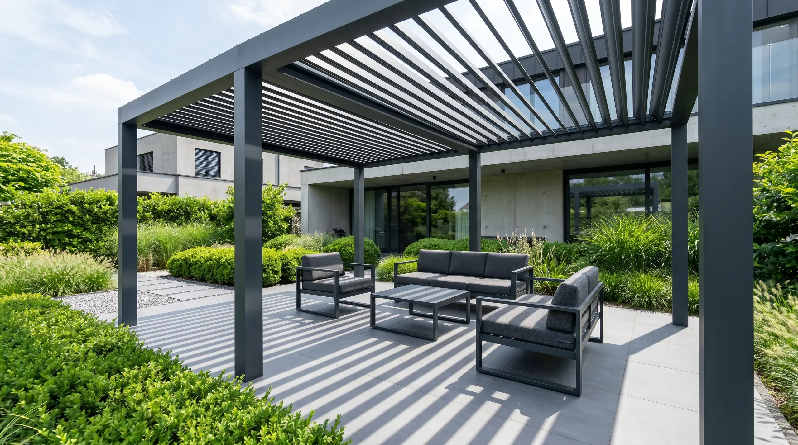 Pergola metalowa z regulowanymi lamelami na tarasie z meblami wypoczynkowymi i zielonym ogrodem