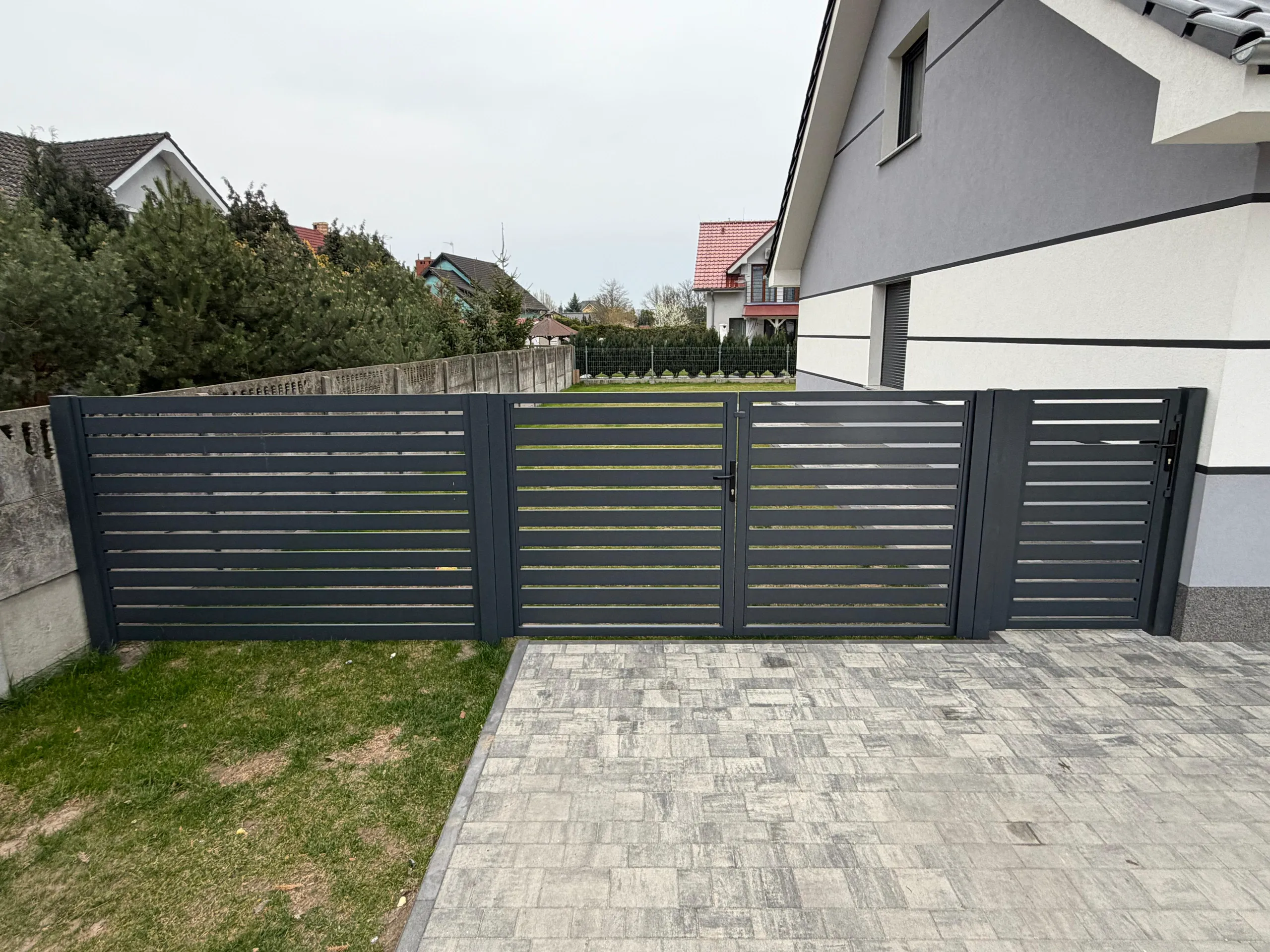 Grafitowe ogrodzenie żaluzjowe z poziomymi listwami przy nowoczesnym domu